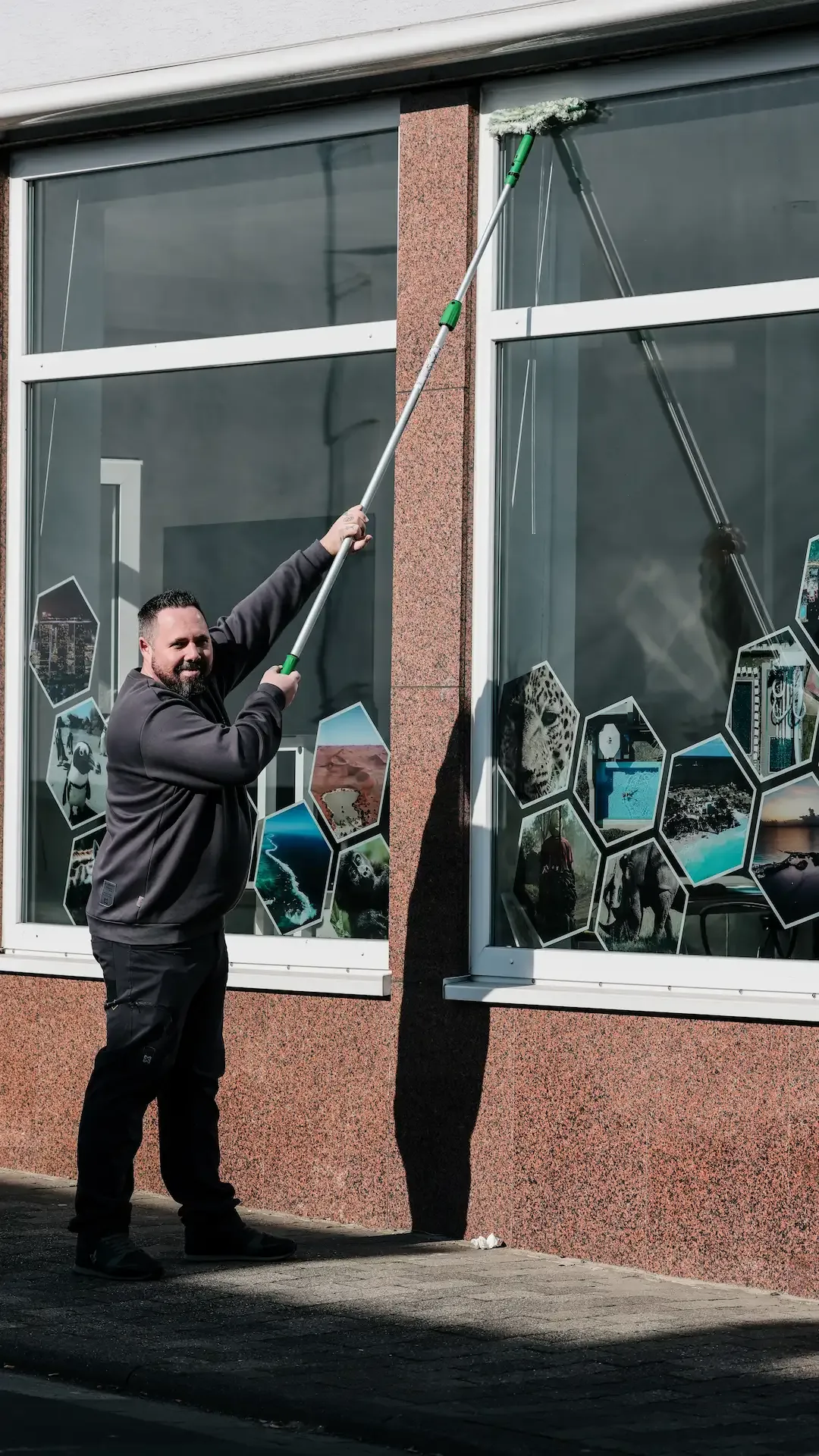 Fensterreinigung mit Teleskopstange an einer Hausfassade
